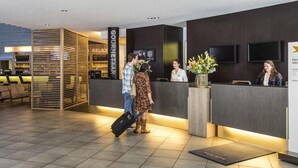 Un espace d’accueil d’hôtel au design moderne, comprenant un comptoir d’accueil, un coin salon et un bar.