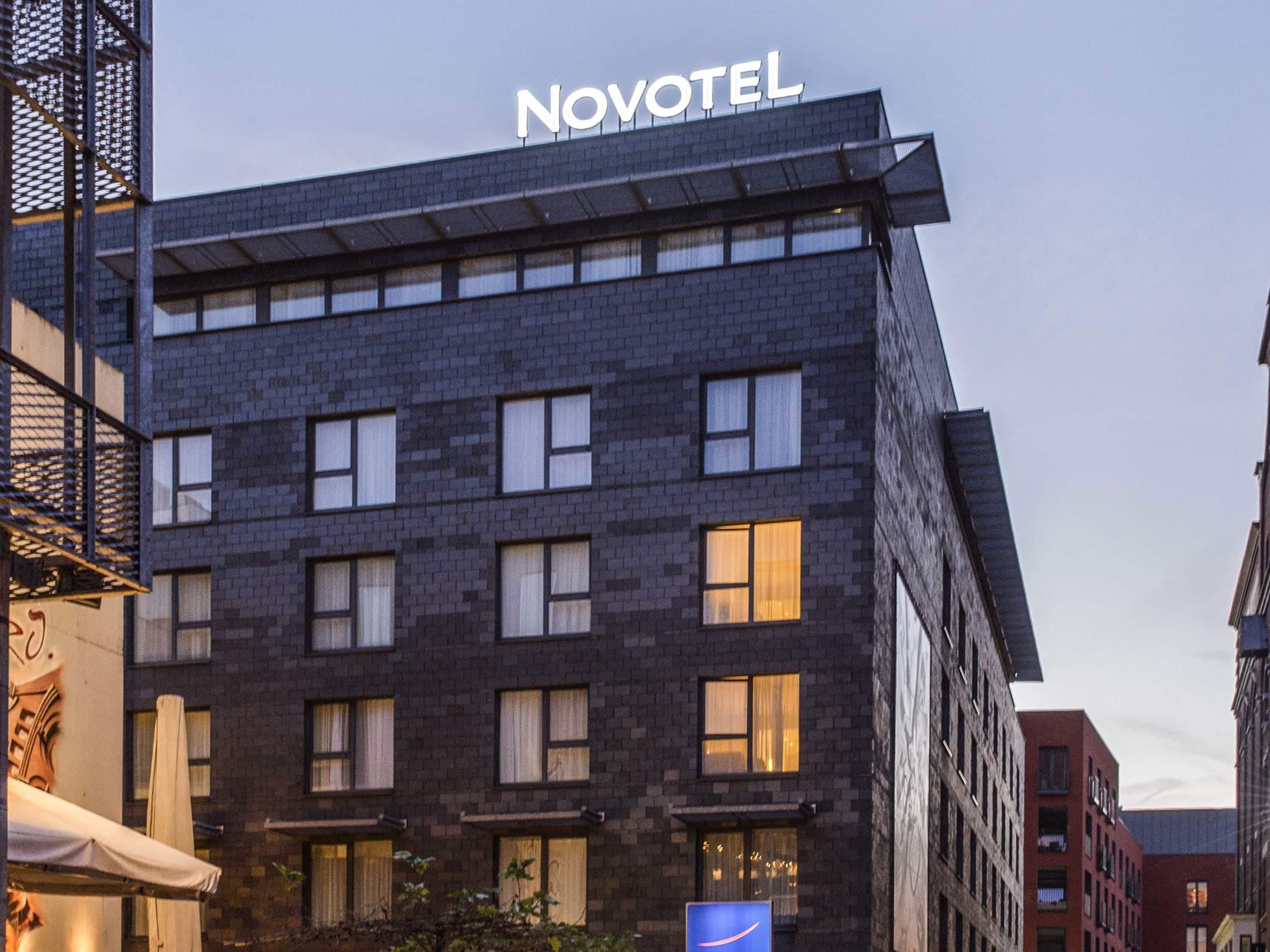 Un hôtel moderne, reconnaissable à son grand panneau « NOVOTEL » placé en haut de l’immeuble.
