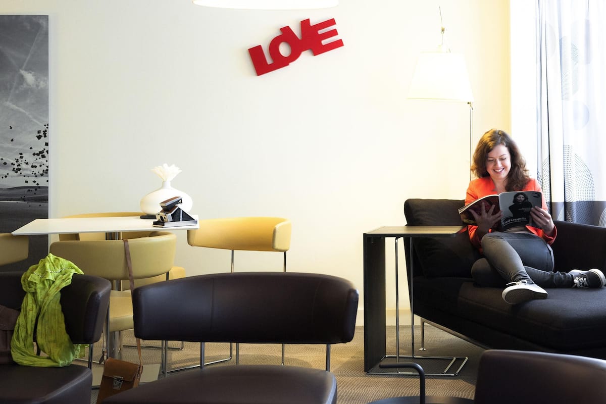 A modern hotel room with a sofa, a table, and a lamp.