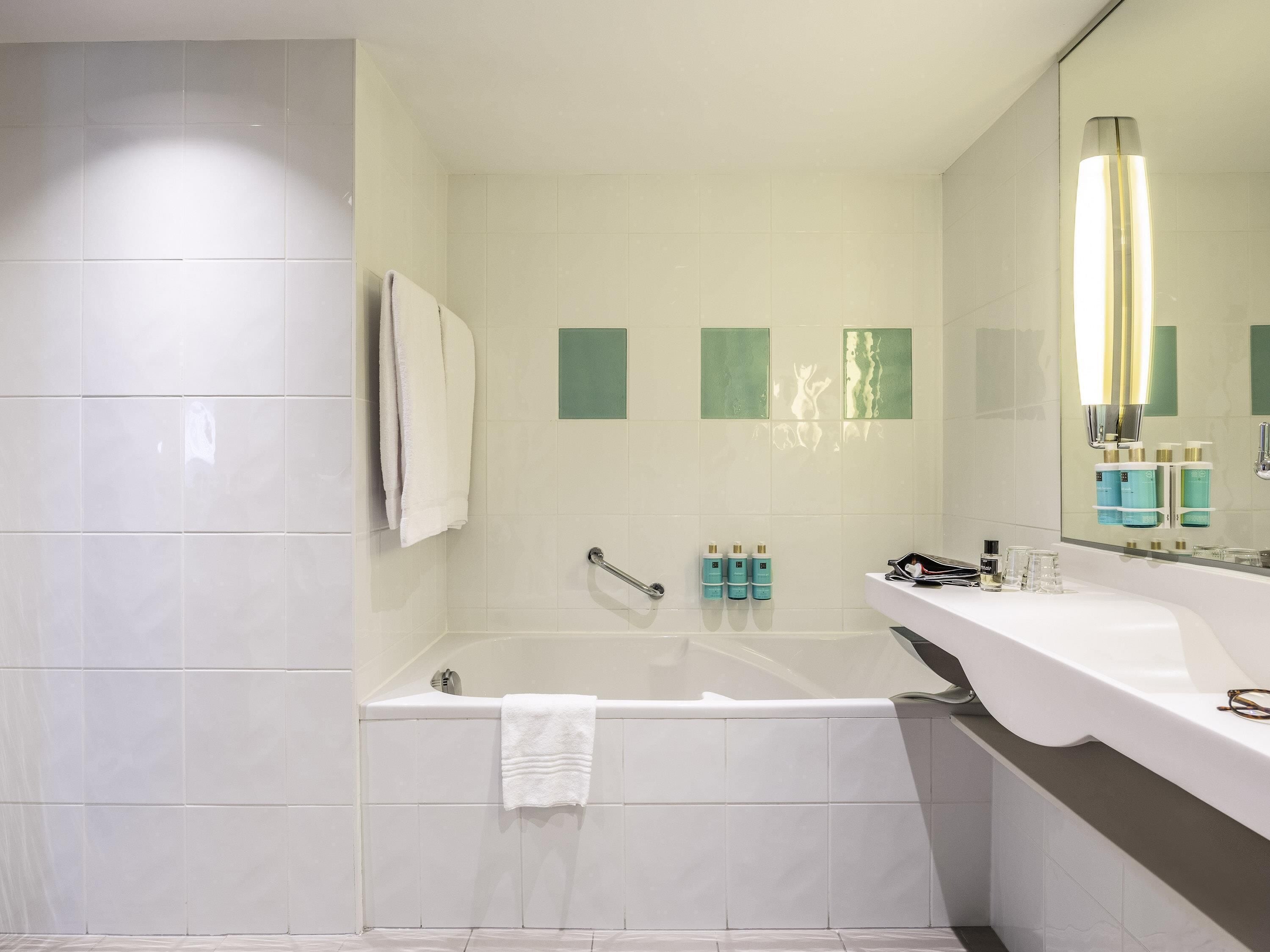 A modern bathroom with a bathtub, a white sink, and a large mirror.
