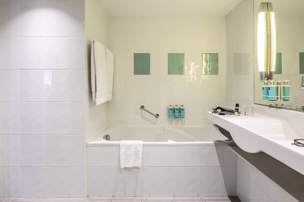 A modern bathroom with a bathtub, a white sink, and a large mirror.