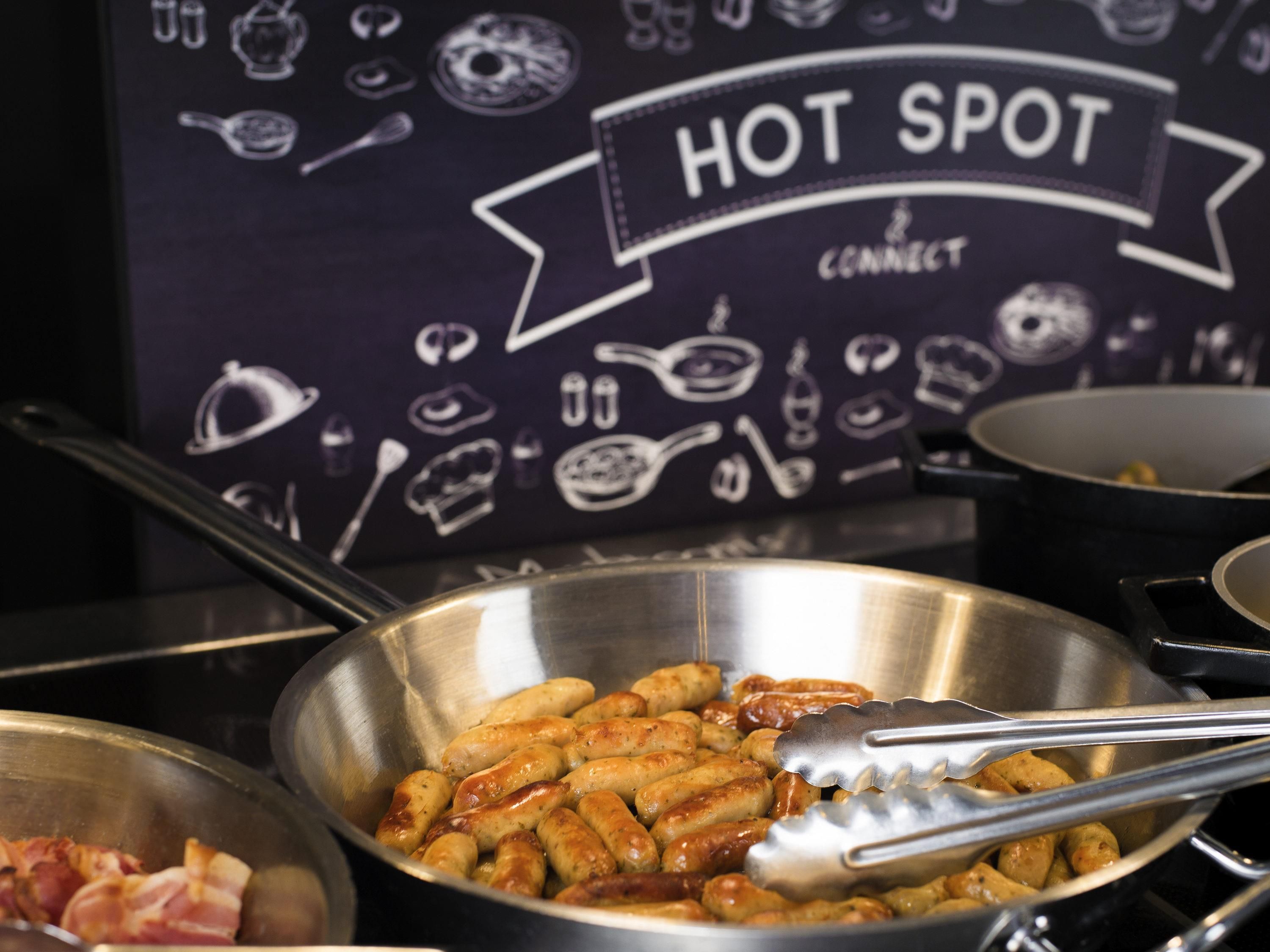 A kitchen area with a sign reading 'HOT SPOT CONNECT' and a bowl of cooked sausages.