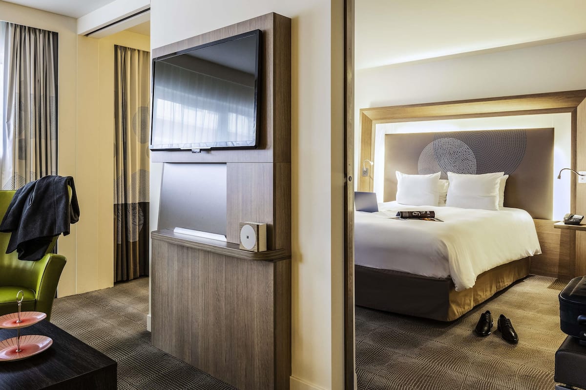 Una habitación de hotel con cama, mesita de noche y televisor en la pared.