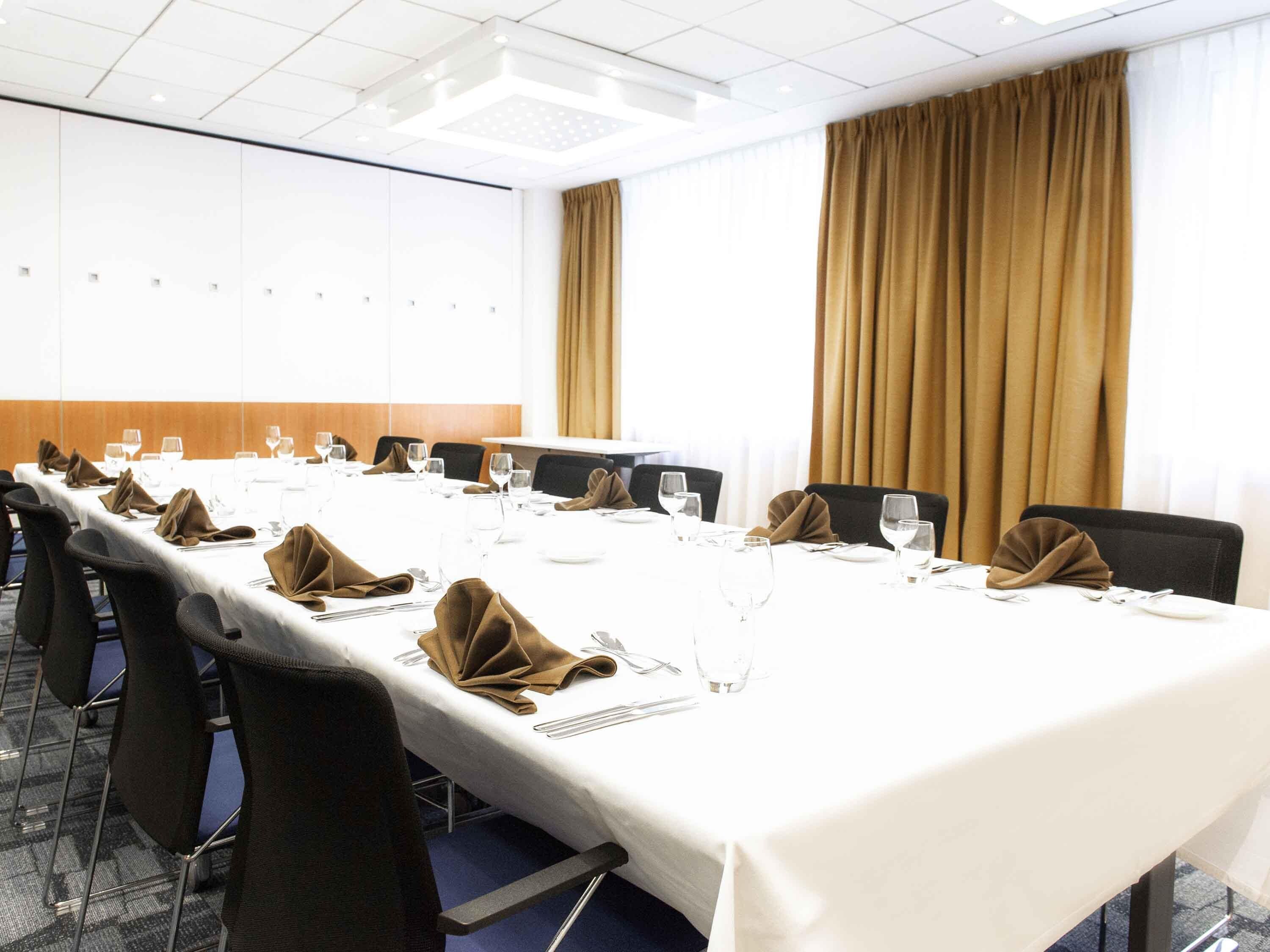 A conference room with a long table, chairs, and a white tablecloth.