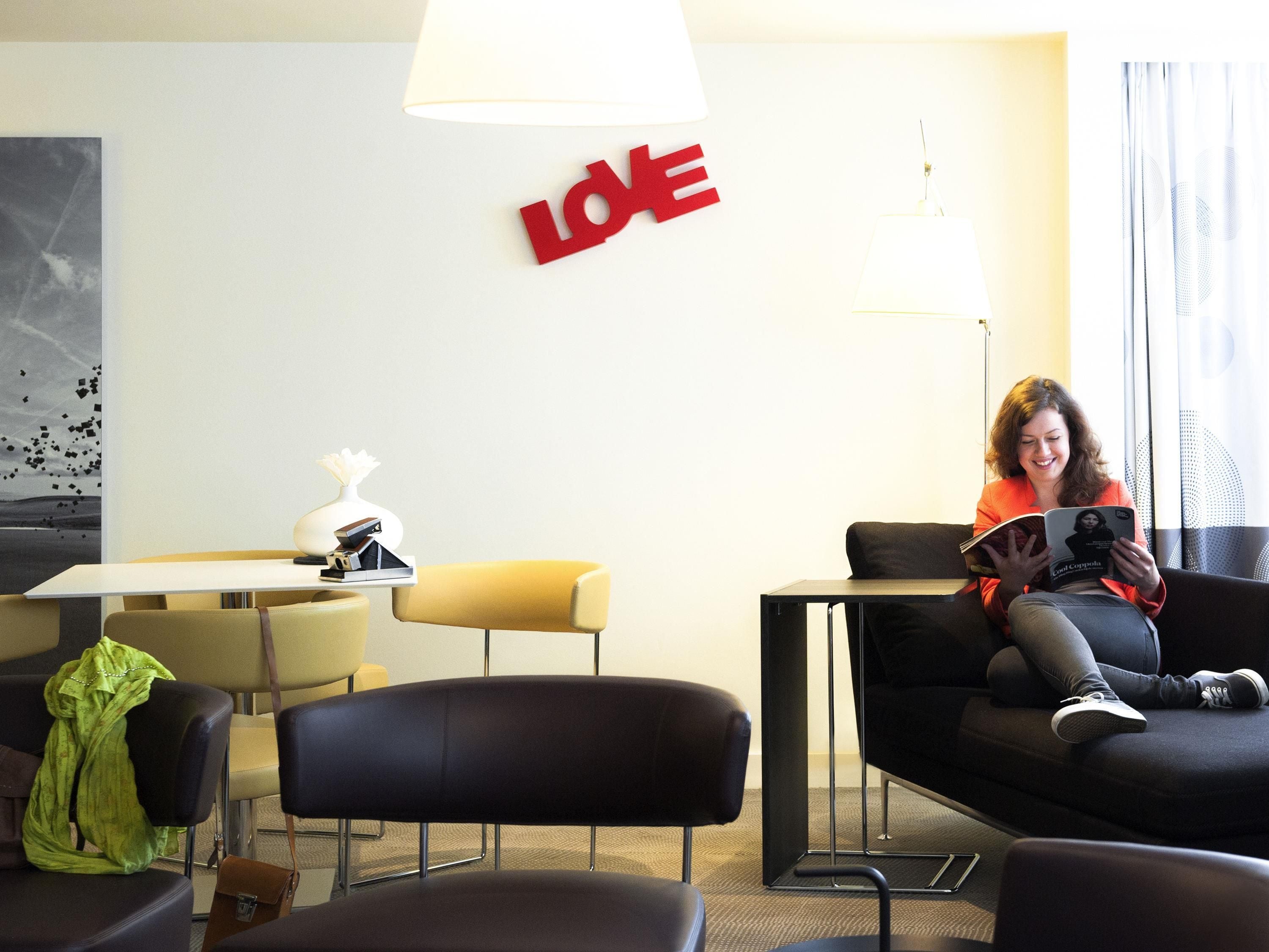 Una habitación de hotel moderna con sofá, mesa y lámpara.