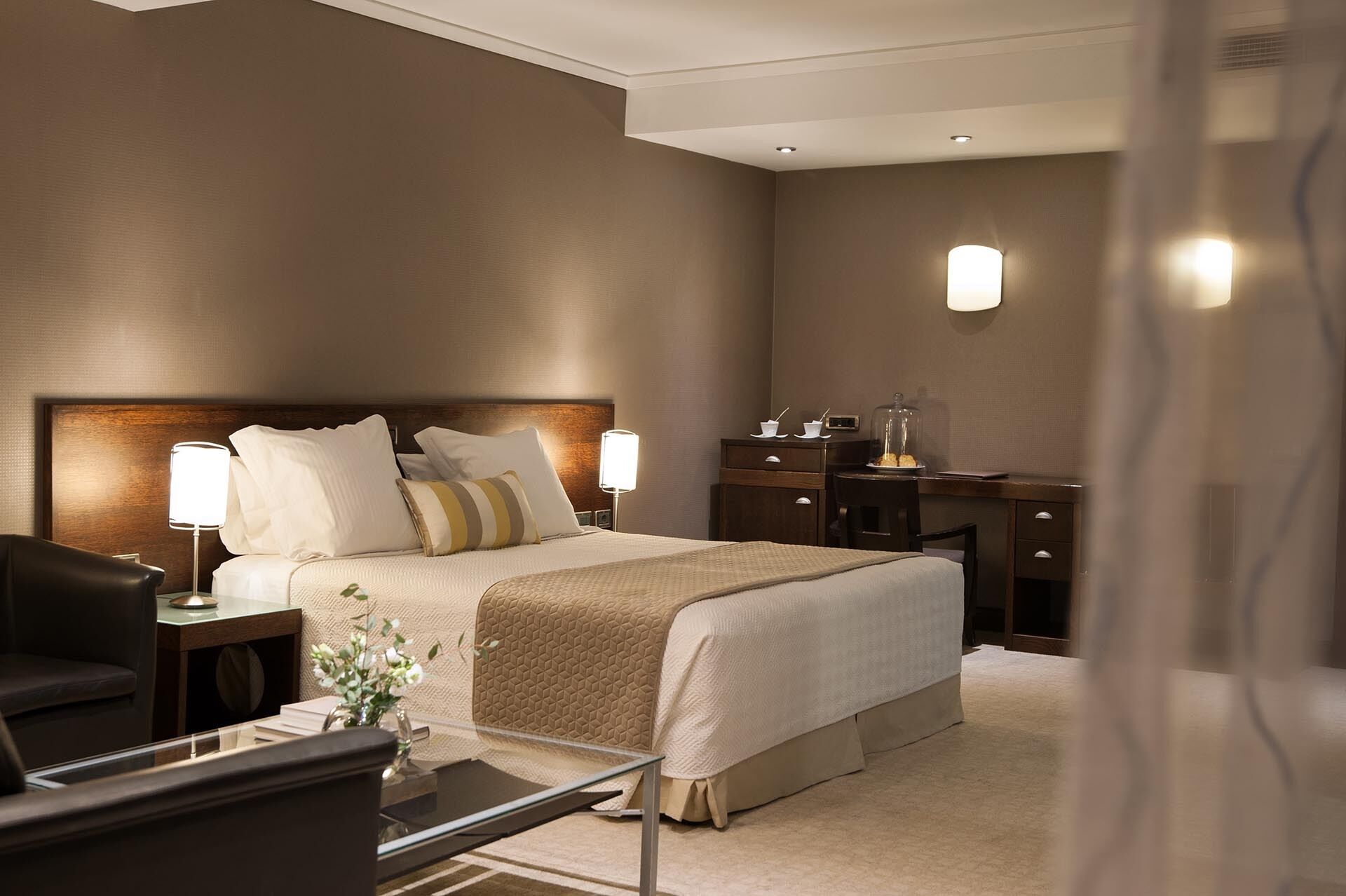Une chambre d’hôtel avec un grand lit, des lampes de chevet, un bureau et une chaise.