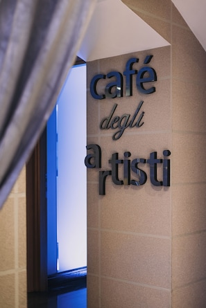 En vägg med en skylt där det står ”café degli artisti”.