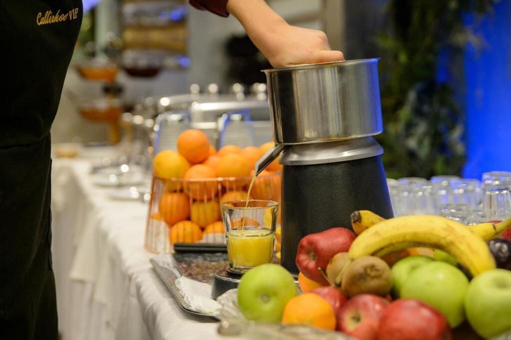 A buffet setup with a variety of fruits and a beverage dispenser.