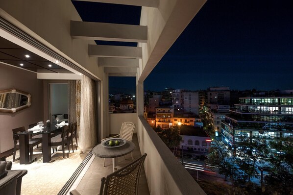 A balcony with a dining area, a chair, and a table with a fruit bowl. - Athenian Callirhoe Hotel (Athens)