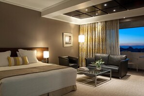 Habitación de hotel con una cama grande, un escritorio, una silla y vistas a la ciudad.