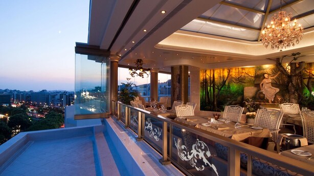 A restaurant with a view of the city, modern interior design, and a chandelier. - Athenian Callirhoe Hotel (Athens)