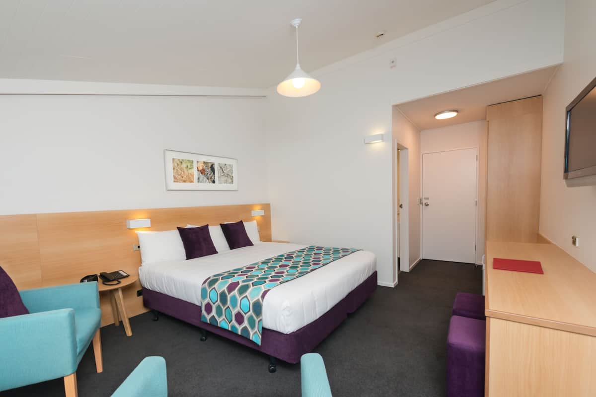 Ein Hotelzimmer mit Bett, Schreibtisch, Stuhl und einem kleinen Tisch.