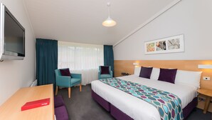 A hotel room with a bed, two chairs, a desk, and a TV. - Heartland Hotel Fox Glacier (Fox Glacier)