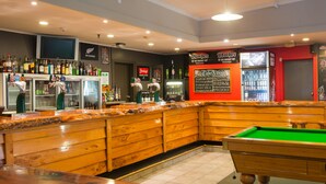A bar area with a pool table, bar counter with bottles, and a chalkboard menu. - Heartland Hotel Fox Glacier (Fox Glacier)