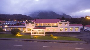A two-story building with a red roof, multiple windows, and a well-lit entrance. - Heartland Hotel Fox Glacier (Fox Glacier)