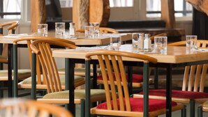 A restaurant with wooden tables and chairs, some with red cushions. - Heartland Hotel Fox Glacier (Fox Glacier)