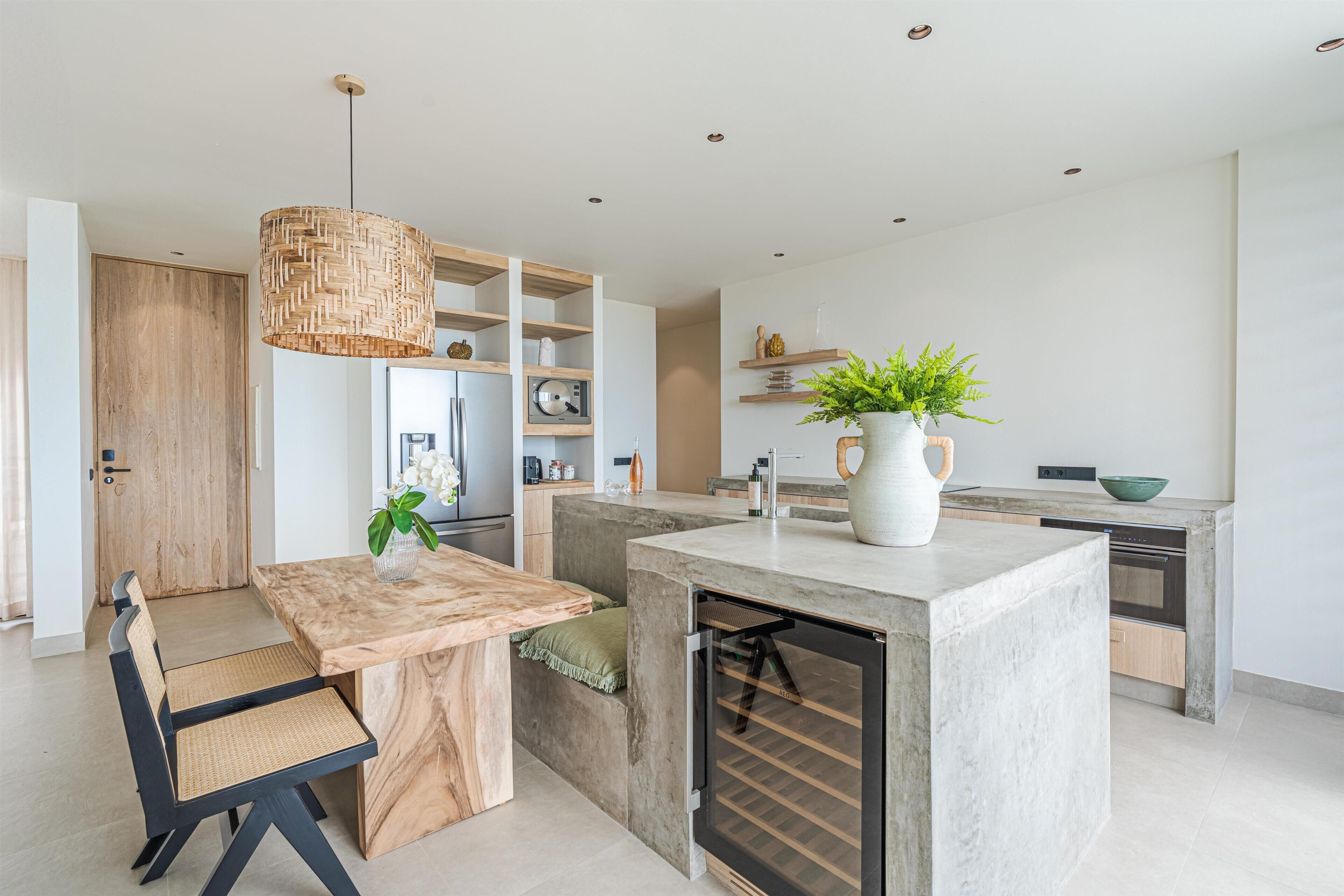 Una cocina moderna con una isla central, estanterías integradas y una lámpara colgante.
