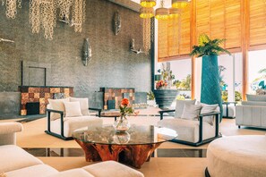 Un hall d’entrée moderne avec une table basse en verre, des canapés et une grande plante en pot.