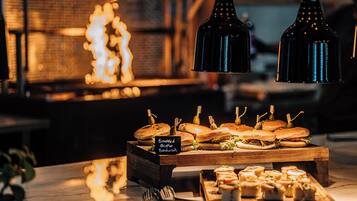 A buffet with sandwiches and appetizers, a sign indicating 'Smoked Chicken Sandwich', and hanging pendant lights.