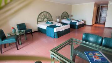 A hotel room with two single beds, a small table with a vase, and a glass table with a book.