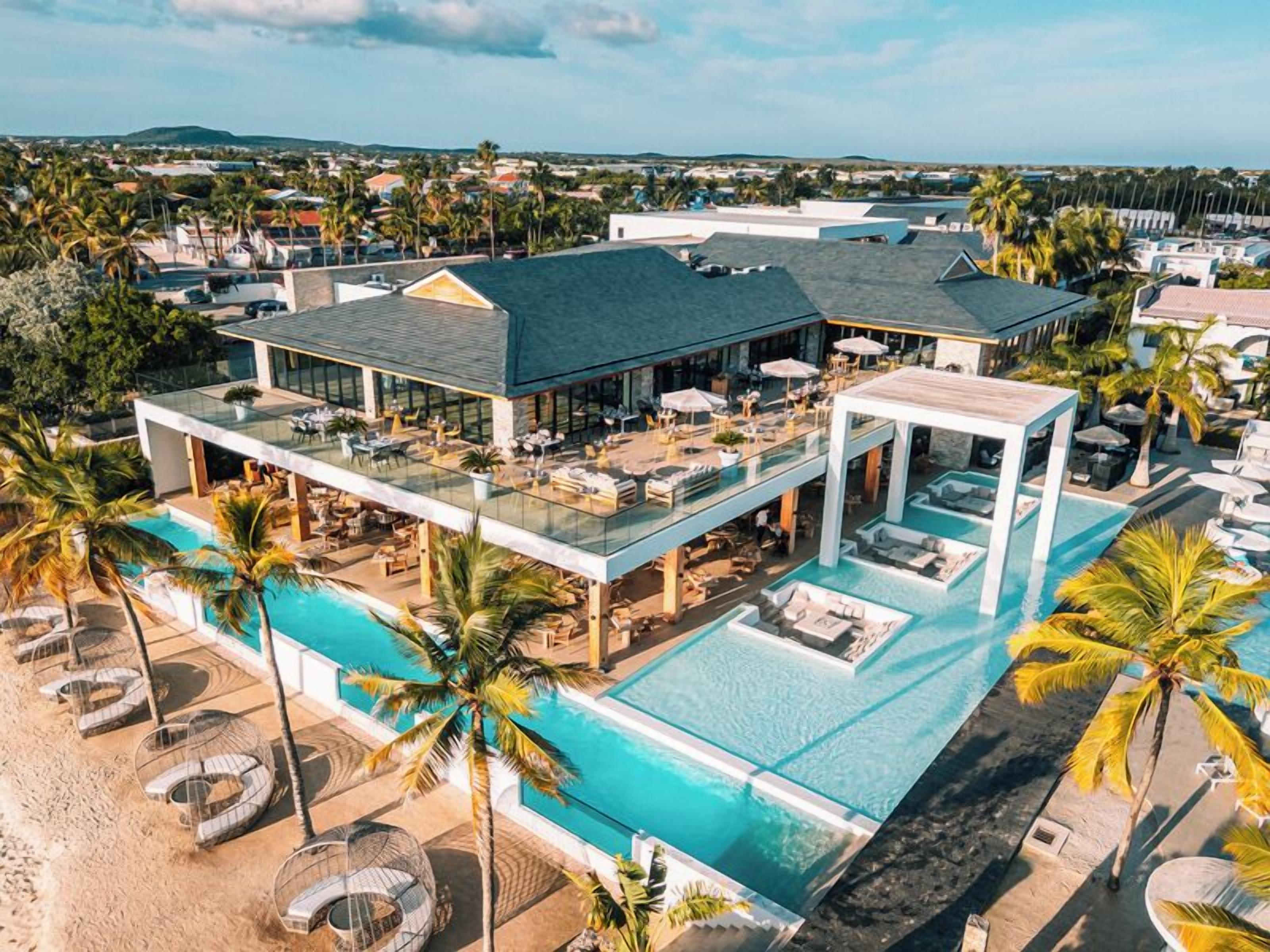 Un complexe hôtelier moderne doté d’une grande piscine, d’espaces de détente en plein air et offrant une vue sur le paysage environnant.
