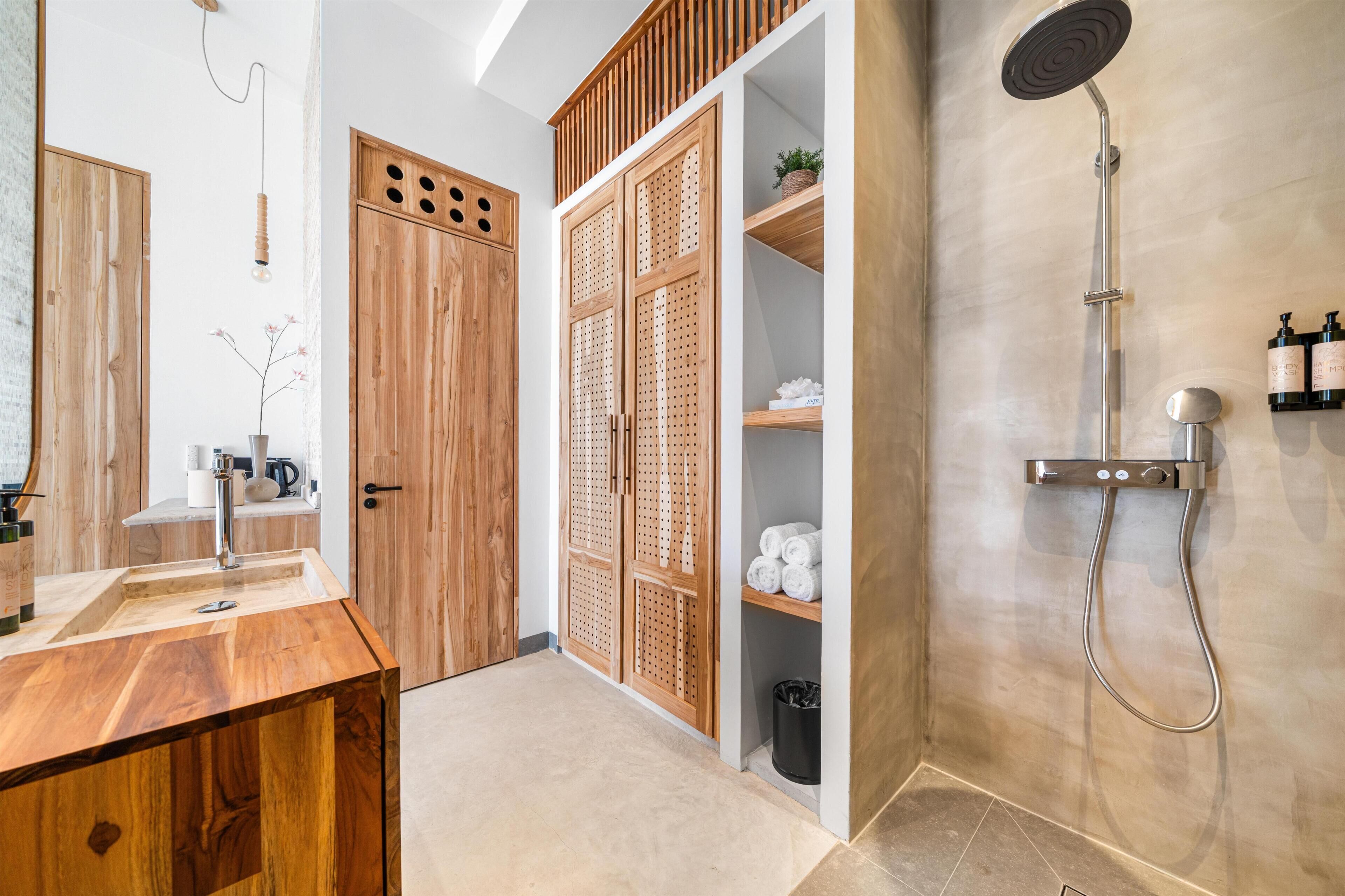 A bathroom with a wooden vanity, a shower, and a storage cabinet.