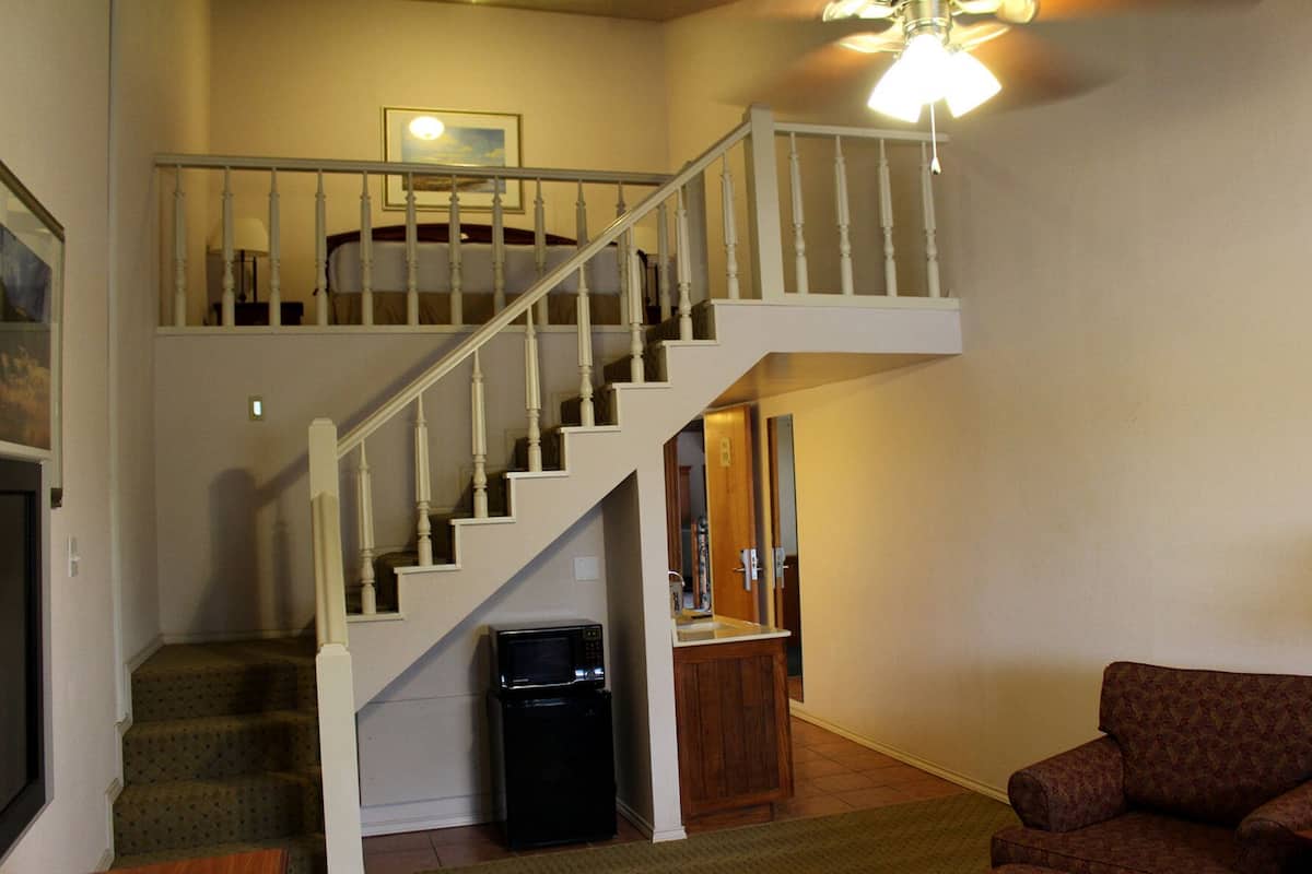 A two-story home with a white staircase, a microwave, and a wooden cabinet.