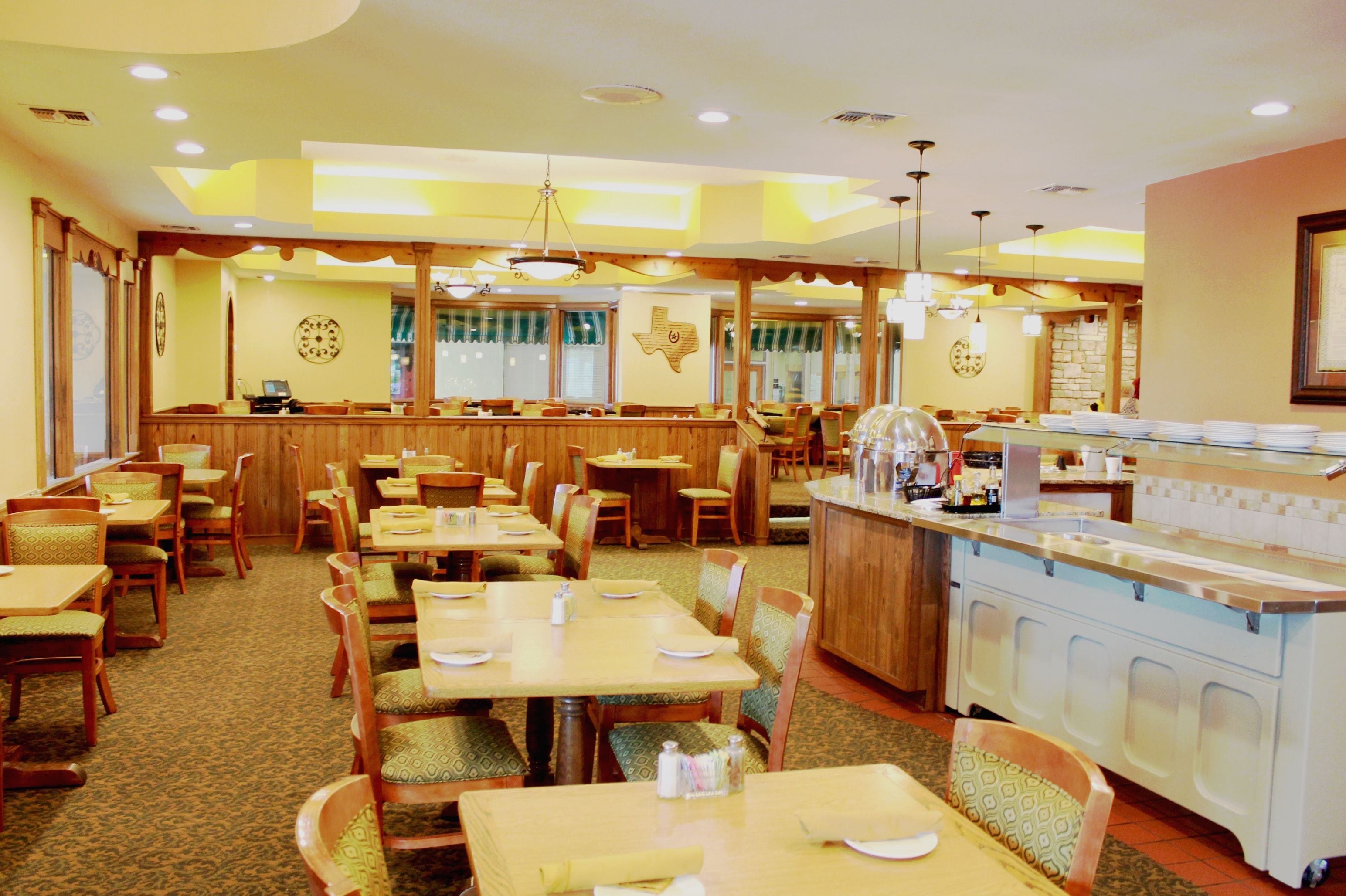 A restaurant with wooden tables and chairs, a bar area, and a kitchen counter.