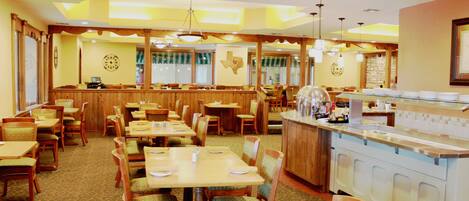 A restaurant with wooden tables and chairs, a bar area, and a kitchen counter.