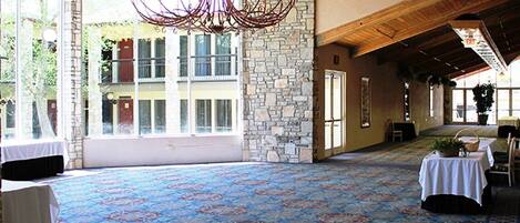 A spacious hall with a patterned carpet, stone walls, and a chandelier.