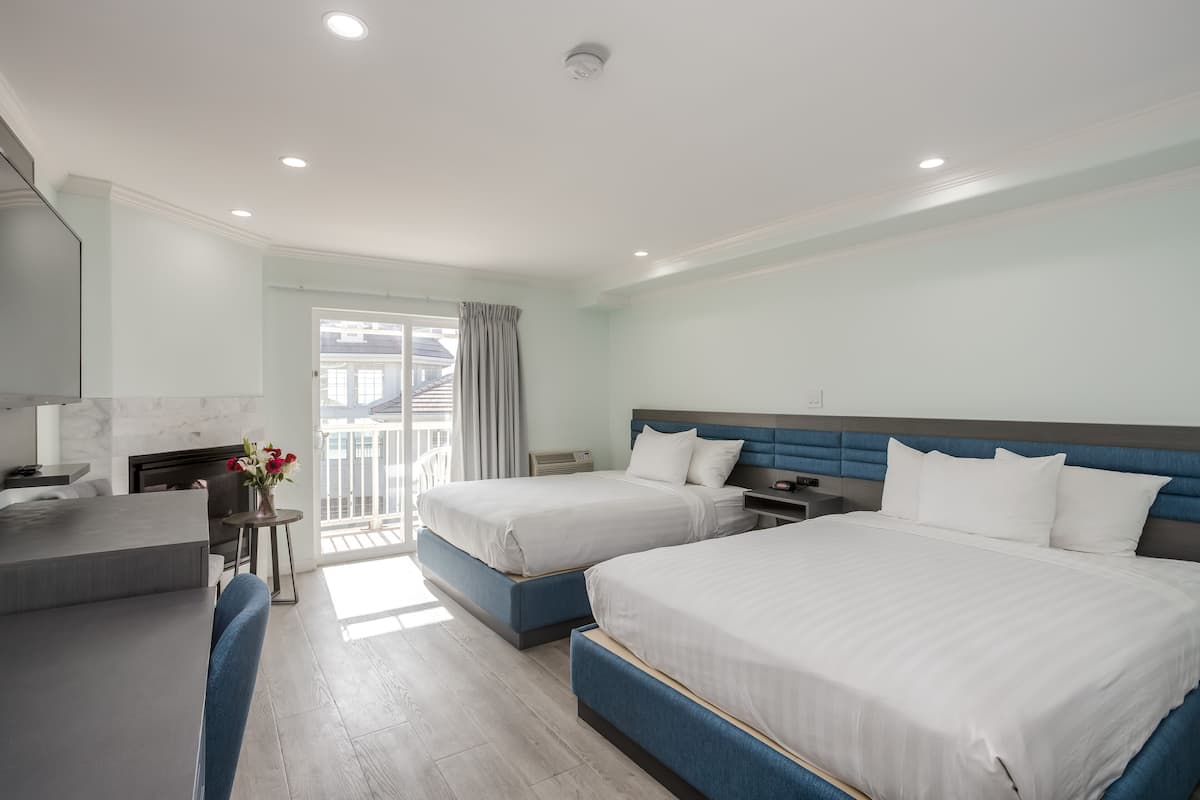 A hotel room with two beds, a desk, and a balcony.