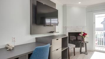 A modern living room with a flat-screen TV mounted on the wall, a built-in fireplace, and a small table with flowers.