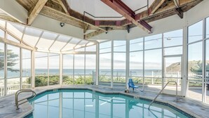 A swimming pool with clear views of the ocean, large windows, and a wooden ceiling structure. - Pacifica Beach Hotel (Pacifica)