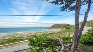 Uma estrada costeira com uma praia e colinas ao fundo.