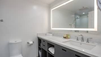 A modern bathroom with a white sink, a large mirror, and a toilet.
