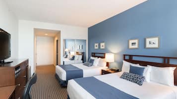 A hotel room with two beds, a TV, a desk, and a mirror.