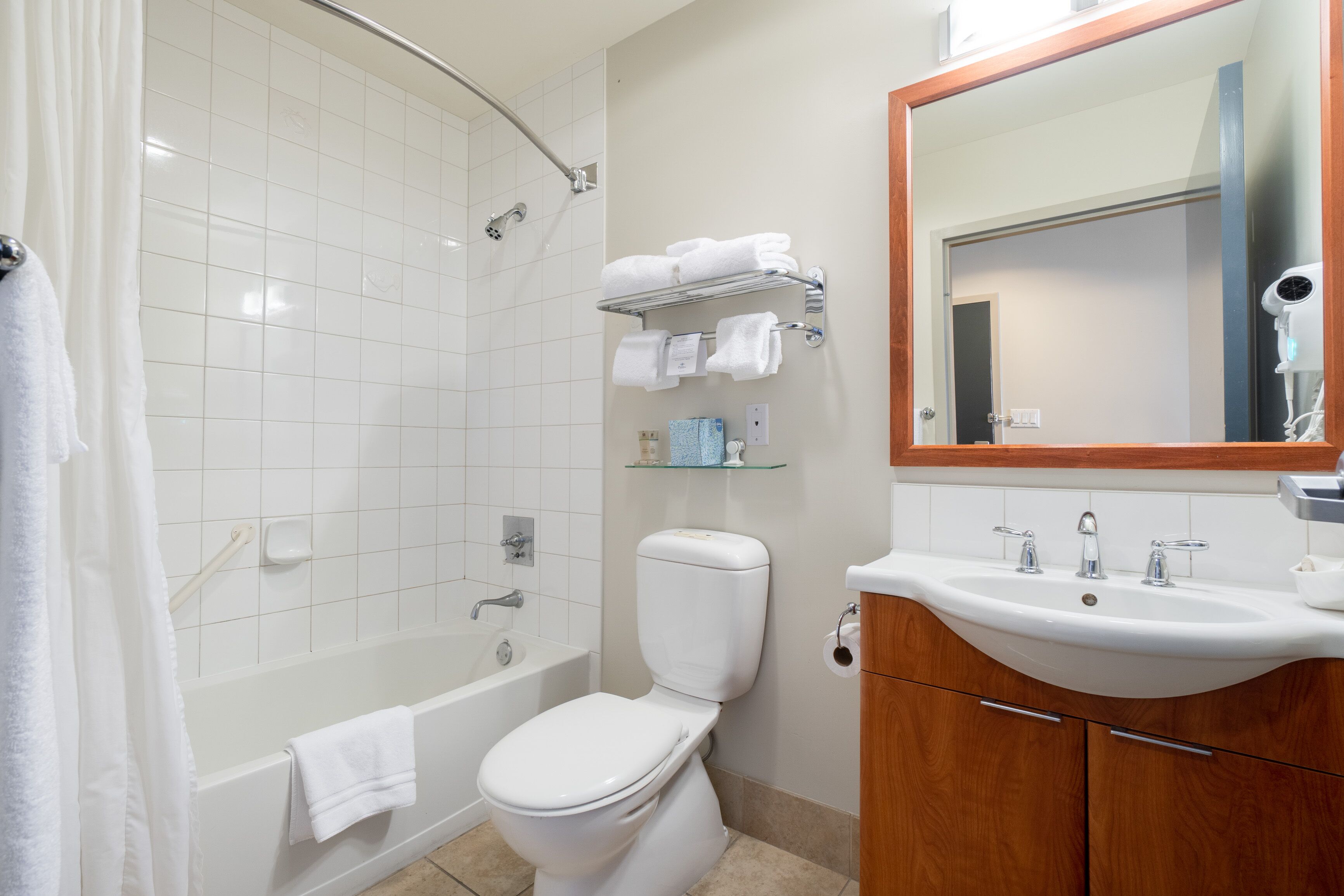 Un baño con ducha, inodoro, lavamanos y espejo.