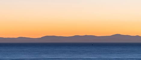 Mar tranquila al atardecer con montañas a lo lejos.