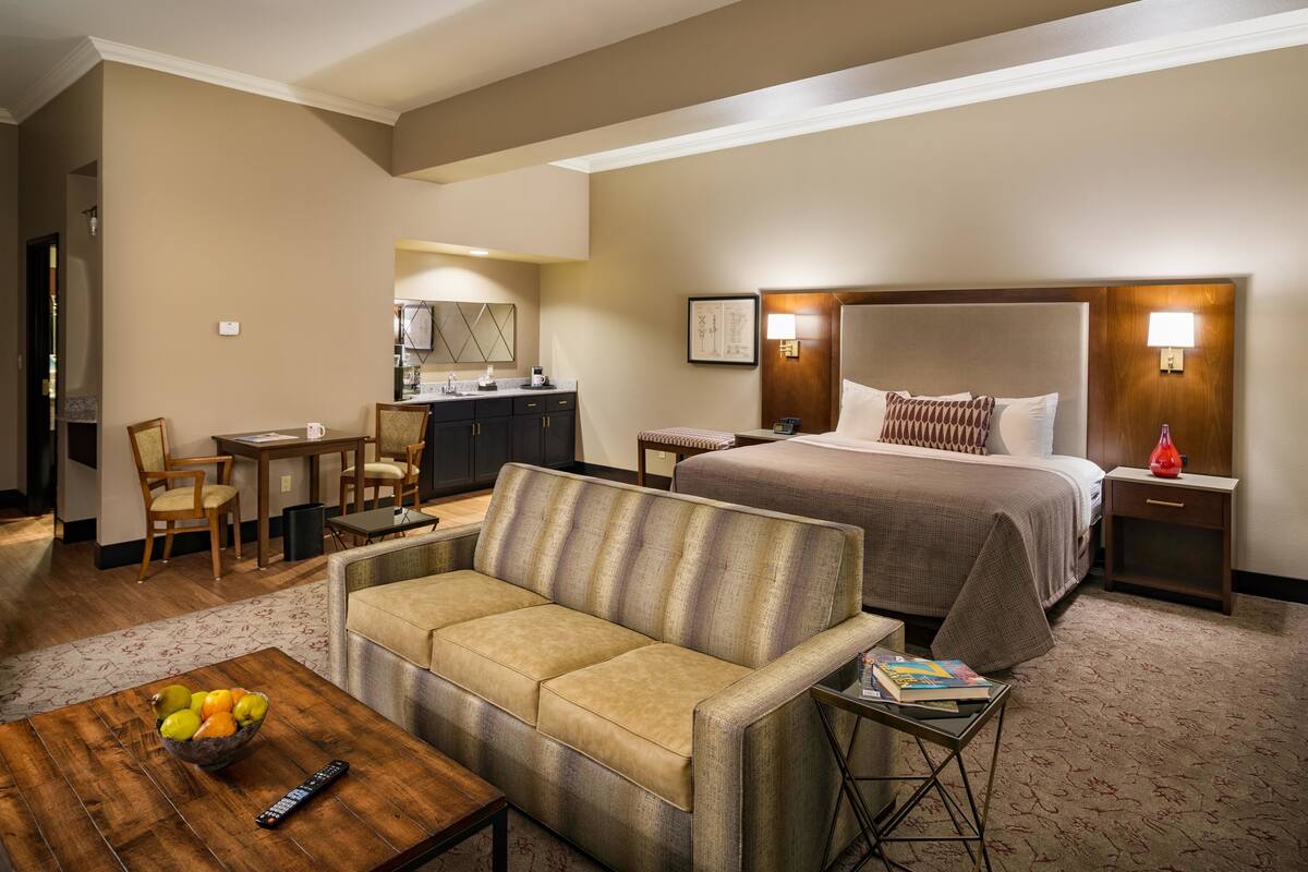 Een hotelkamer met een bed, een slaapbank, een eettafel en een kitchenette.