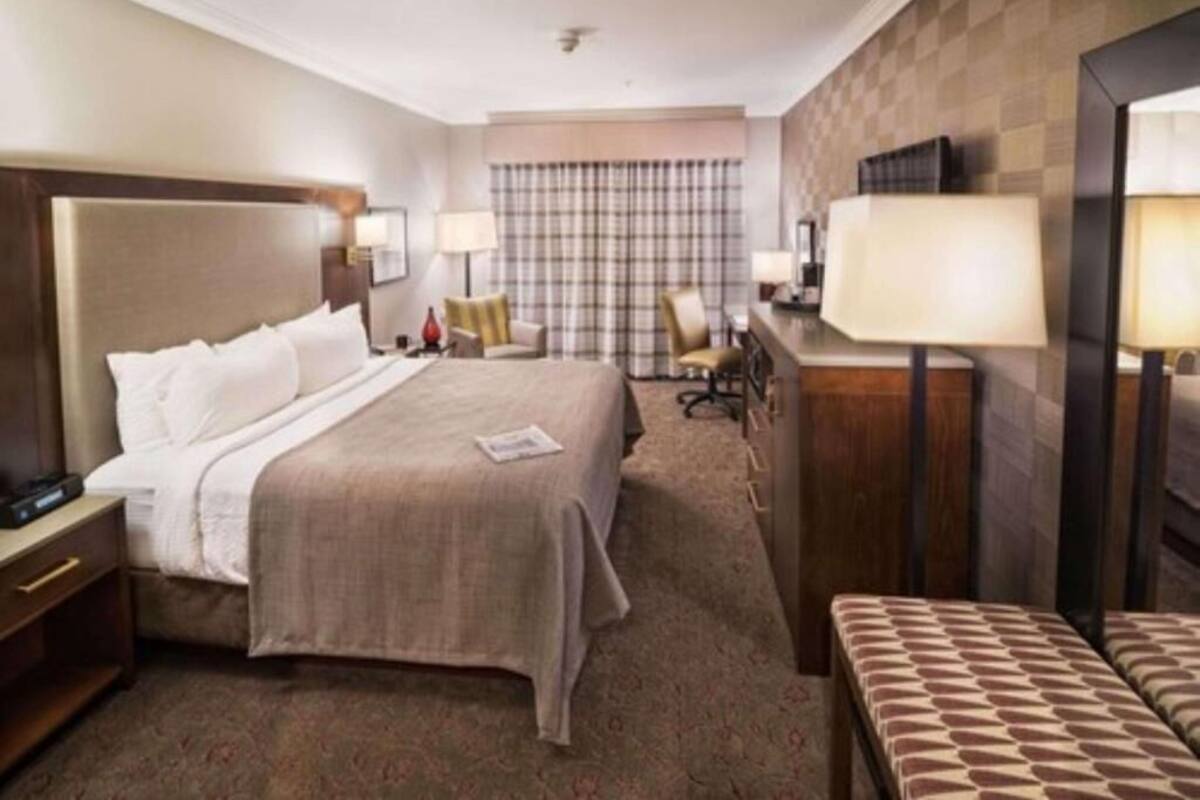 Een hotelkamer met een groot bed, een bureau, twee stoelen en een bijzettafeltje.