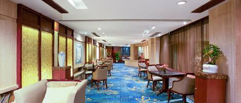 A hotel lobby with a long corridor, seating areas, and a reception desk.