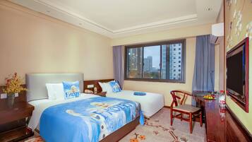 A hotel room with two beds, a desk, a chair, a TV, and a window with a city view.