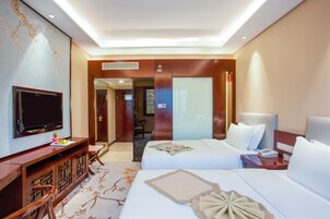 Habitación de hotel con dos camas, televisor, escritorio y espejo.