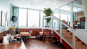 A modern hotel room with a dining area, a kitchen, and a staircase.
