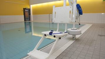 A swimming pool with a starting block, a lifeguard chair, and a clock on the wall.