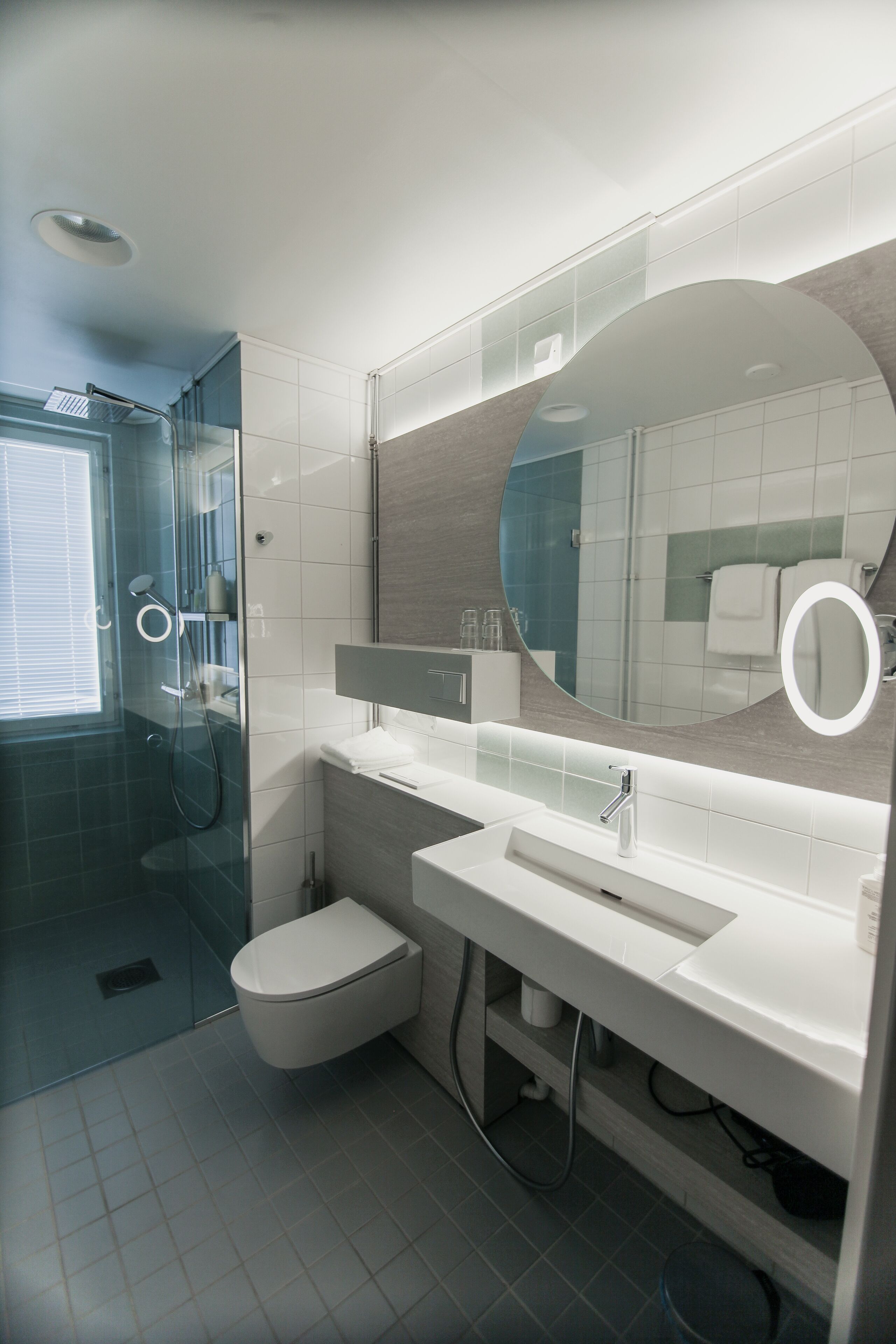 Un baño moderno con cabina de ducha de vidrio, un lavabo blanco y un espejo grande.