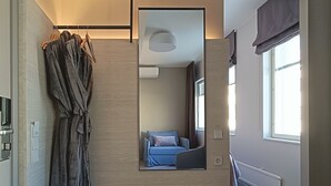 A modern bedroom with a bed, a bedside table, a mirror, and a robe hanging on a rack.