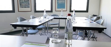 A conference room with tables, chairs, water bottles, and framed pictures on the walls.