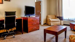 A hotel room with a desk, a television, a chair, a small table, and a door leading to another room. - Comfort Suites Gadsden Attalla (Attalla)