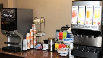 Una estación de café con una máquina de café, varios dispensadores de bebidas y una variedad de cápsulas y tazas de café.